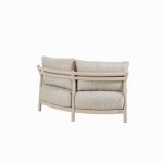 Ein modernes, geschwungenes Sofa in Farbe latte mit einem minimalistischen Holzgestell, das mit zwei großen Sitzkissen und zwei losen Rückenkissen ausgestattet ist. Das Sofa aus der Serie Mykonos von 4SO ist von hinten schräg vor einem weißen Hintergrund abgebildet.