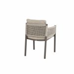 Ein moderner Dining-Stuhl aus der Serie Savanne von 4SO mit Metallgestell, hellbeigen Kissen und geflochtener Rückenlehne. Der Stuhl ist mit der Rückenlehne zum Betrachter gewinkelt und zeigt vier gerade Beine und ein niedriges Rückenkissen auf weißem Grund.