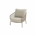 Ein moderner Living-Sessel aus der Serie Martinique von 4SO, mit hellbeigen Kissen und einer geflochtenen Rattan-Rückenlehne mit schlanken, hellbraunen Metallbeinen. Sein minimalistisches Design schafft einen modernen und luftigen Look vor einem schlichten weißen Hintergrund.