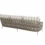 Ein beigefarbenes, geflochtenes Living-Sofa aus der Serie Beverly von 4SO in Farbe latte zeichnet sich durch ein geometrisches, kreuzförmiges Flechtmuster, angewinkelte Beine und drei Rückenkissen mit weißen und beigen Querstreifen aus. Gezeigt wird es in der Rückansicht vor einem schlichten weißen Hintergrund.