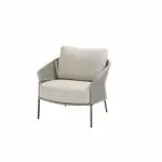 Ein moderner Living-Sessel aus der Serie Florence von 4SO, mit Kissen in der Farbe Terre und einer geschwungenen Rückenlehne. Schlanke Metallbeine und geflochtene, offene Seiten unterstreichen den minimalistischen, modernen Look - perfekt als stilvolle Gartenmöbel. Vor einem schlichten weißen Hintergrund.
