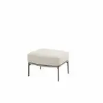 Ein moderner Hocker mit einem hellbeigen, rechteckigen Polsterkissen und schlanken, dunklen Metallbeinen vor einem schlichten weißen Hintergrund. Das Design ist minimalistisch und funktional.