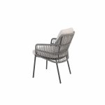 Ein moderner Diningstuhl aus der Serie Alicante von 4SO mit einem geflochtenen grauen Rahmen, abgewinkelten Beinen und breiten Armlehnen. Dieser elegante Gartenmöbel-stuhl ist mit hellbeigen Sitz- und Rückenkissen ausgestattet, die auf einem schlichten weißen Hintergrund stehen.