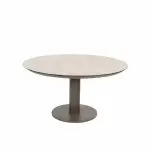 Ein runder Tisch mit einer hellen, glatten Platte und einem einzelnen dunklen Sockel in der Mitte, der auf einer runden Bodenplatte steht. Das Design ist modern und minimalistisch und steht vor einem schlichten weißen Hintergrund.